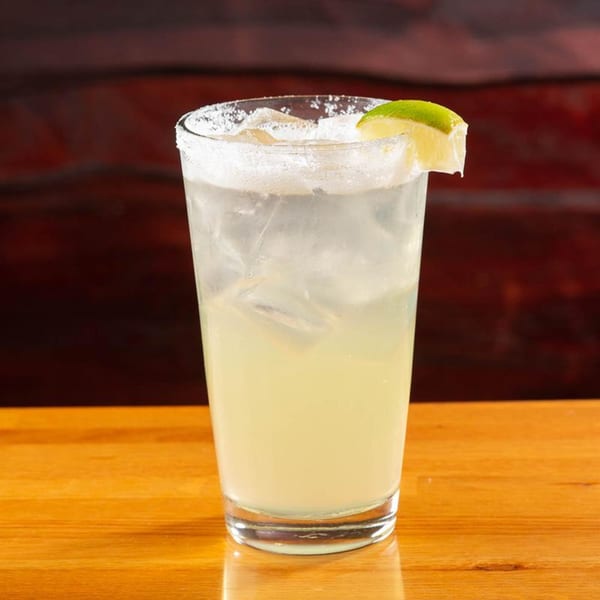 A Vivio's II margarita with a salted rim and lime wedge on a wooden table.