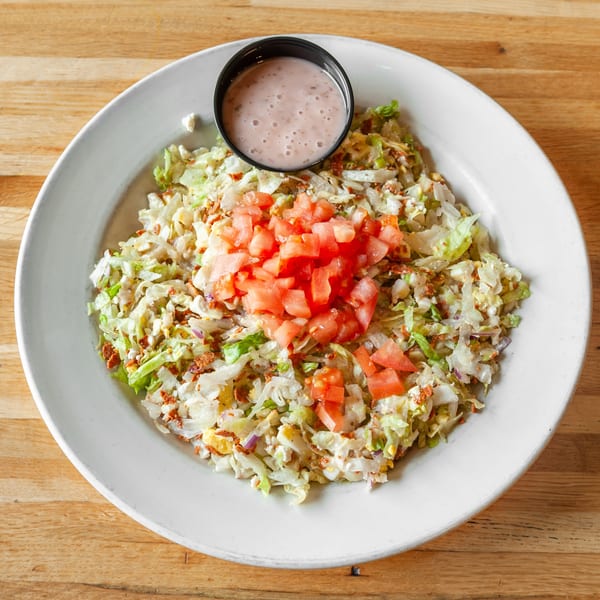 A Vivio's II Food & Spirits chopped salad with tomatoes and dressing on a white plate.