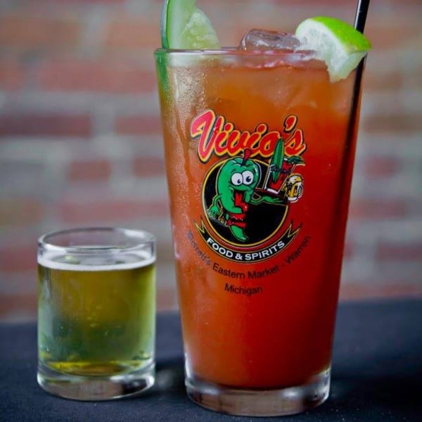A Vivio's Bloody Mary with lime and cucumber, next to a shot glass of beer.
