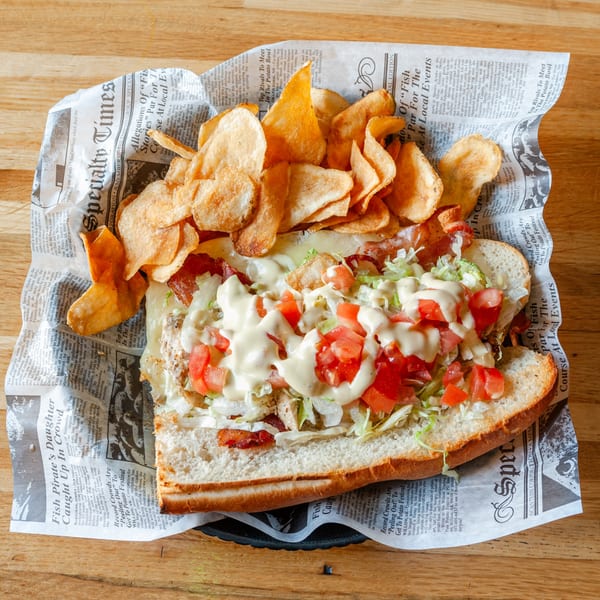 A Vivio's II Food & Spirits sub sandwich with chips, served on newspaper-lined basket.